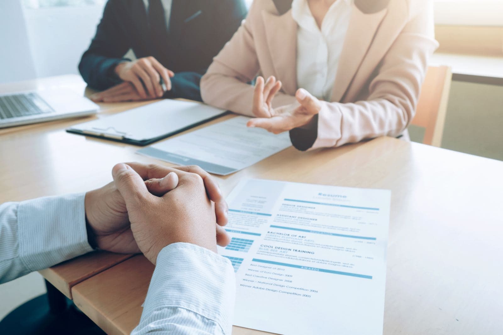 A candidate sitting across from two interviewers reviewing a resume